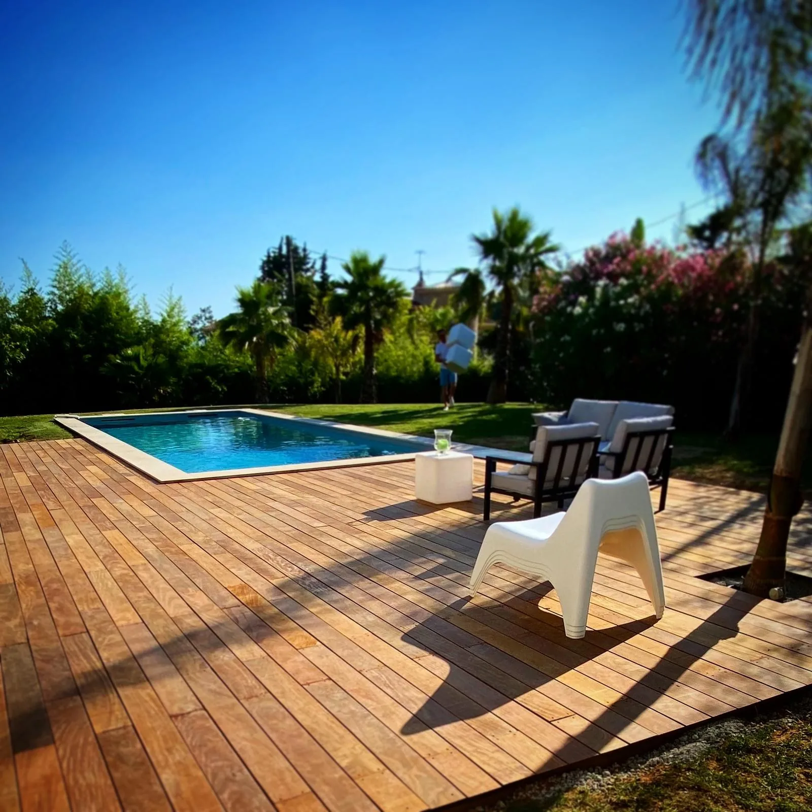 Plage de piscine en bois ipé finie, mobilier de jardin et soleil rasant — après aménagement