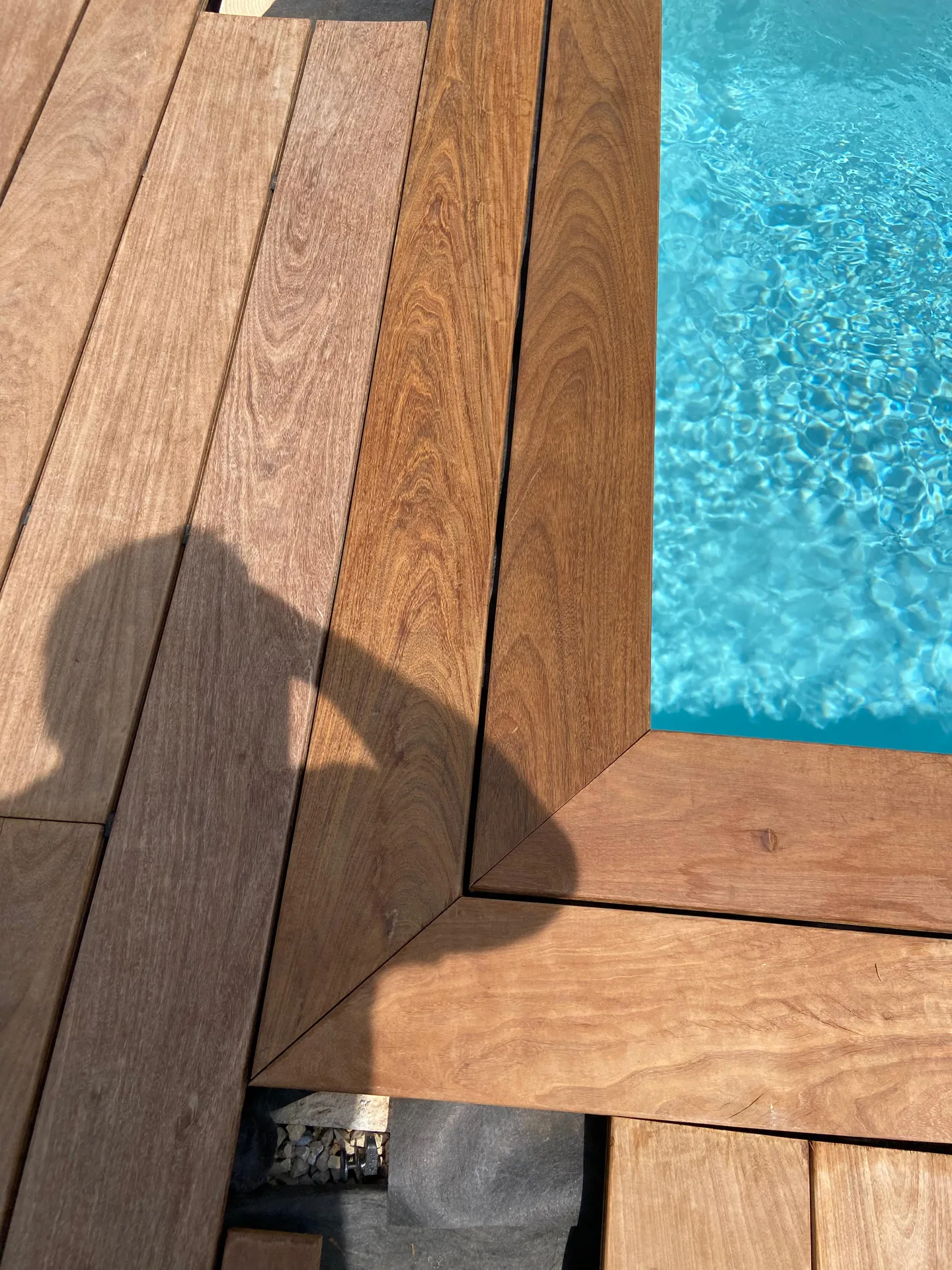 Détail de margelle bois ipé contre piscine bleue turquoise